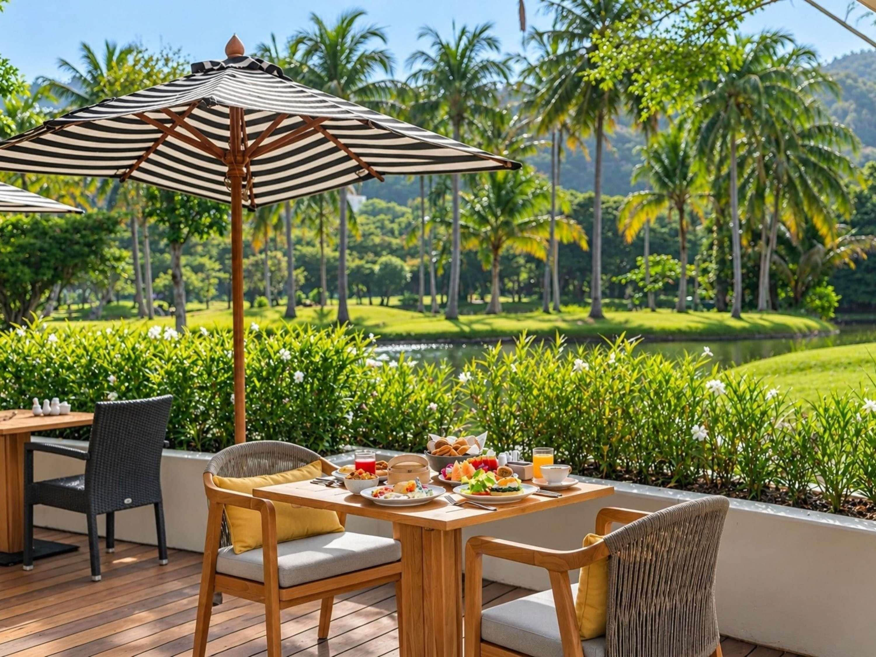 An outdoor dining area with a table set for breakfast, surrounded by lush greenery and palm trees.