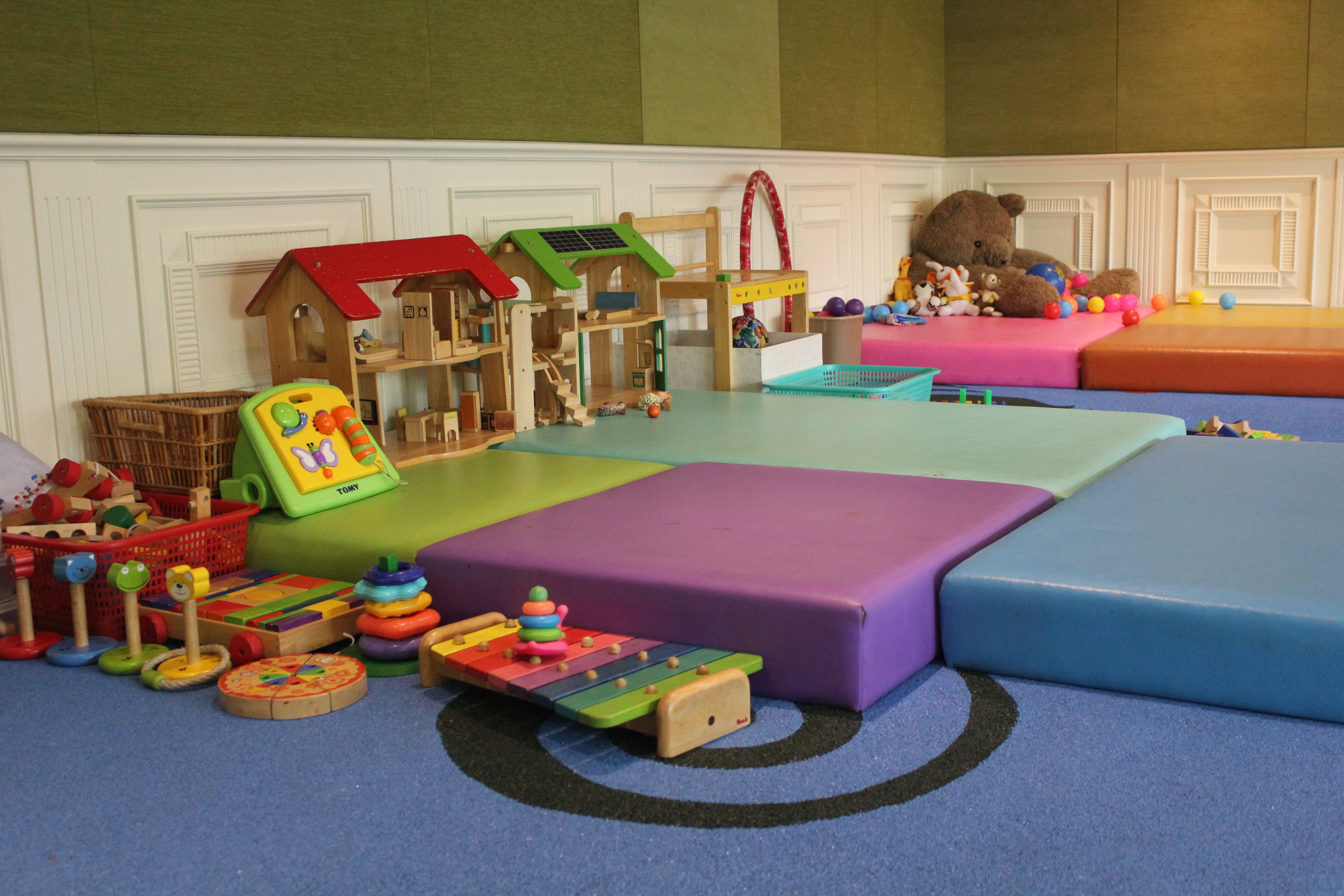 A play area with a wooden playhouse, a slide, and various toys.