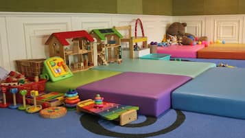 A play area with a wooden playhouse, a slide, and various toys.