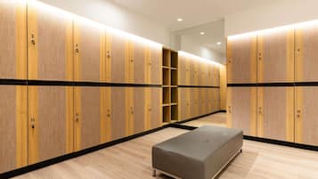Un vestuario moderno con taquillas de madera, un banco y un muro con espejos.
