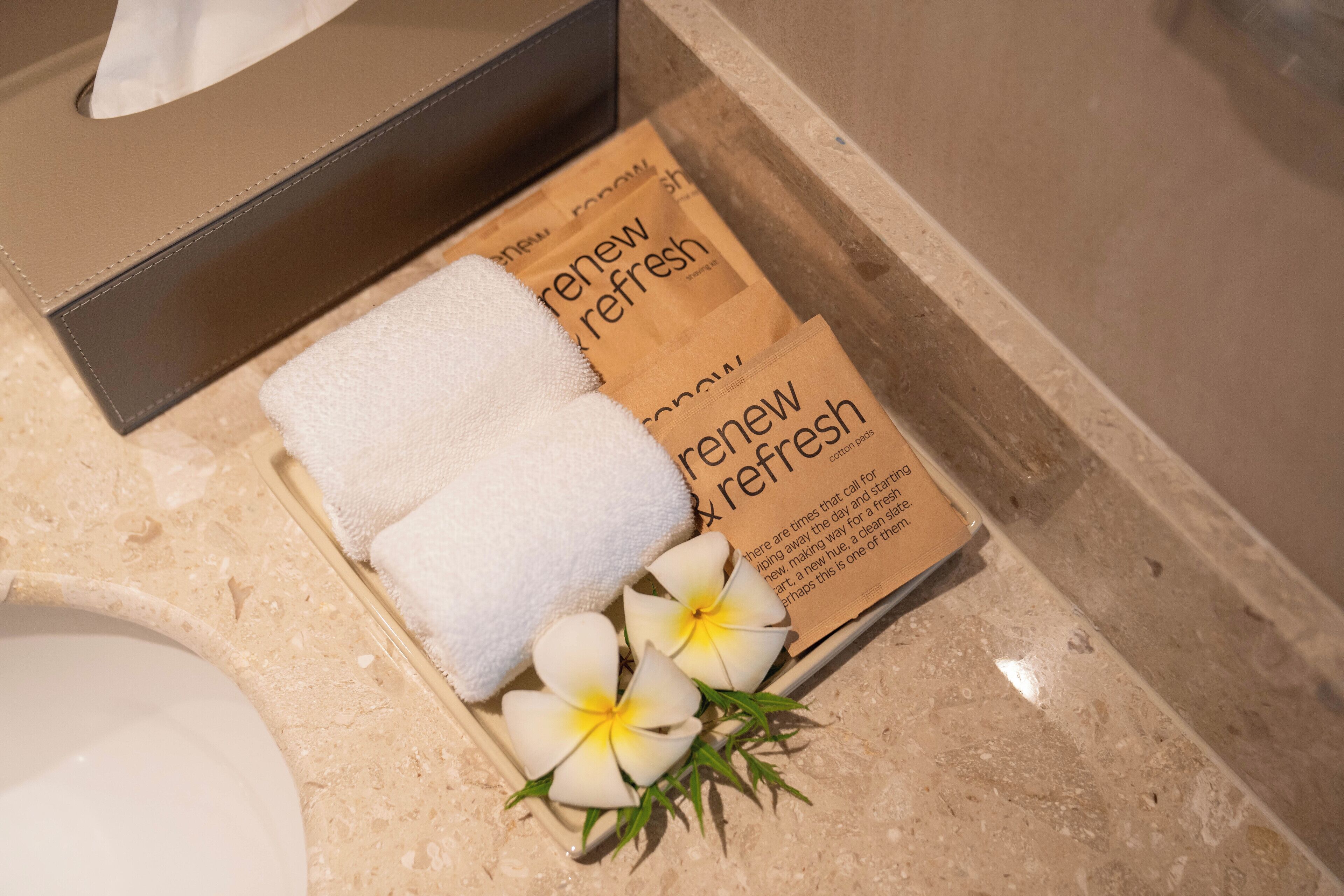 A bathroom with a tissue box, a towel, and a box of 'renew fresh' products.