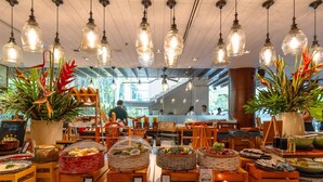 A restaurant with hanging light fixtures, a variety of food displays, and a view of the outdoors. - Pullman Phuket Karon Beach Resort (Karon)