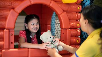 Un enfant tenant un ours en peluche à l’intérieur d’une structure de jeu.