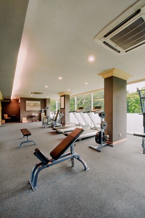 A gym with exercise equipment, benches, and a large window. - The Papandayan (Bandung)