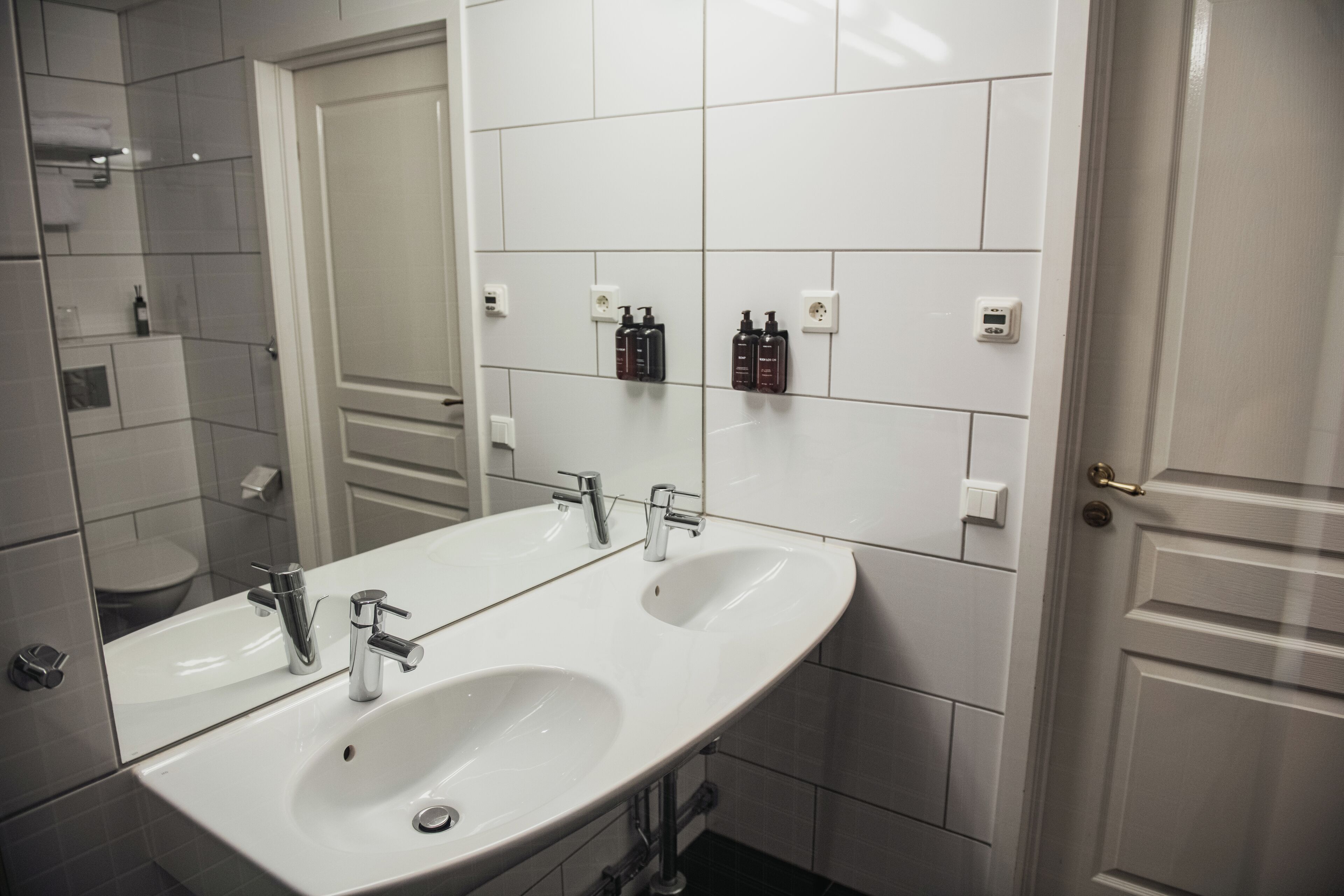Un baño con dos lavamanos, un espejo grande y una zona de ducha.