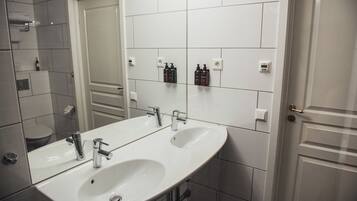 Un baño con dos lavamanos, un espejo grande y una zona de ducha.