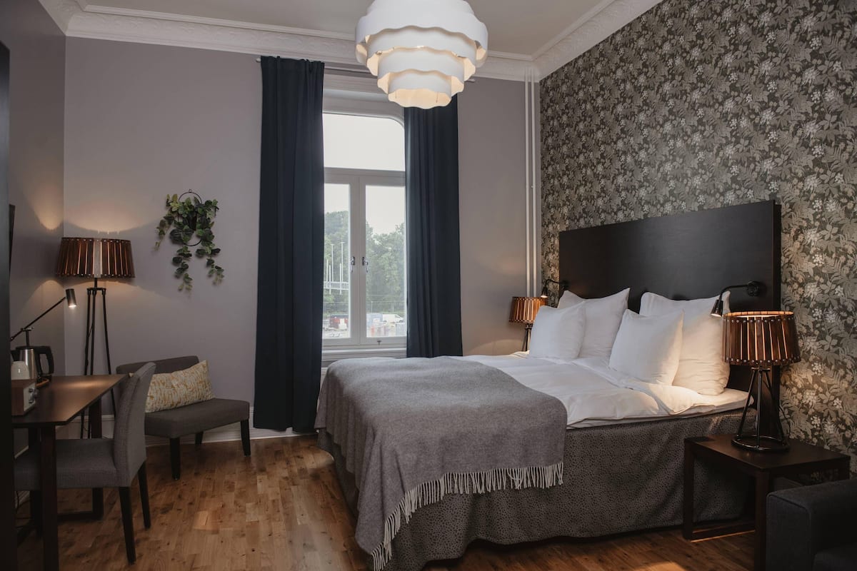 A hotel room with a bed, bedside tables, a desk, and a chair.