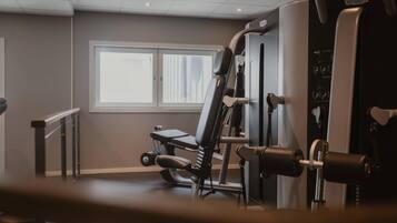 Un gimnasio con equipo de ejercicio, una ventana y una puerta.