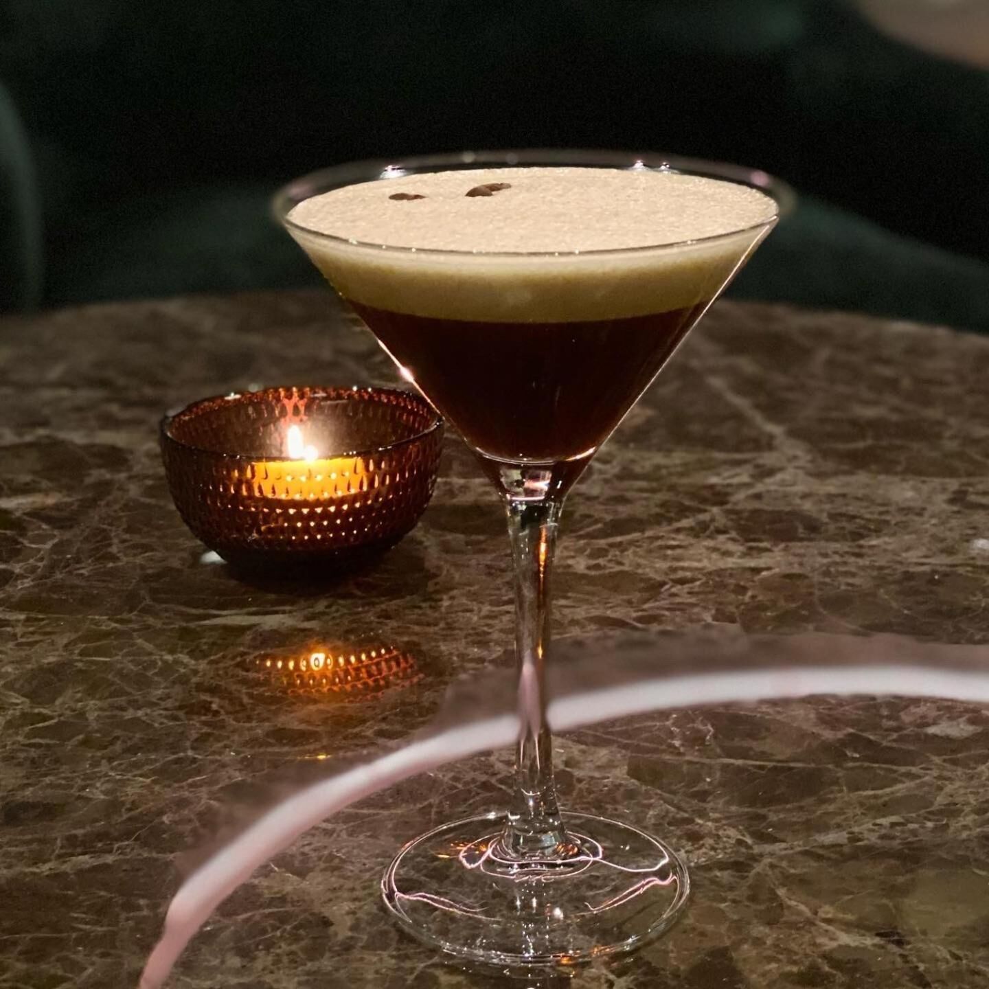 Un verre à martini avec une mousse crémeuse sur une surface en marbre.