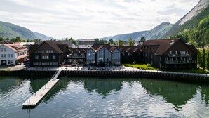Un hôtel situé au bord d’un lac, doté d’une jetée qui s’avance sur l’eau, et entouré de montagnes et de verdure.