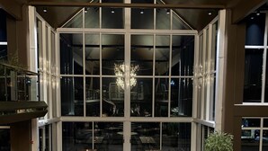Un vaste espace de restauration intérieur, doté de nombreuses tables et chaises, de grandes fenêtres et d’un lustre central.