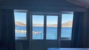 Une chambre d’hôtel dotée d’une grande fenêtre donnant sur la mer et les montagnes.