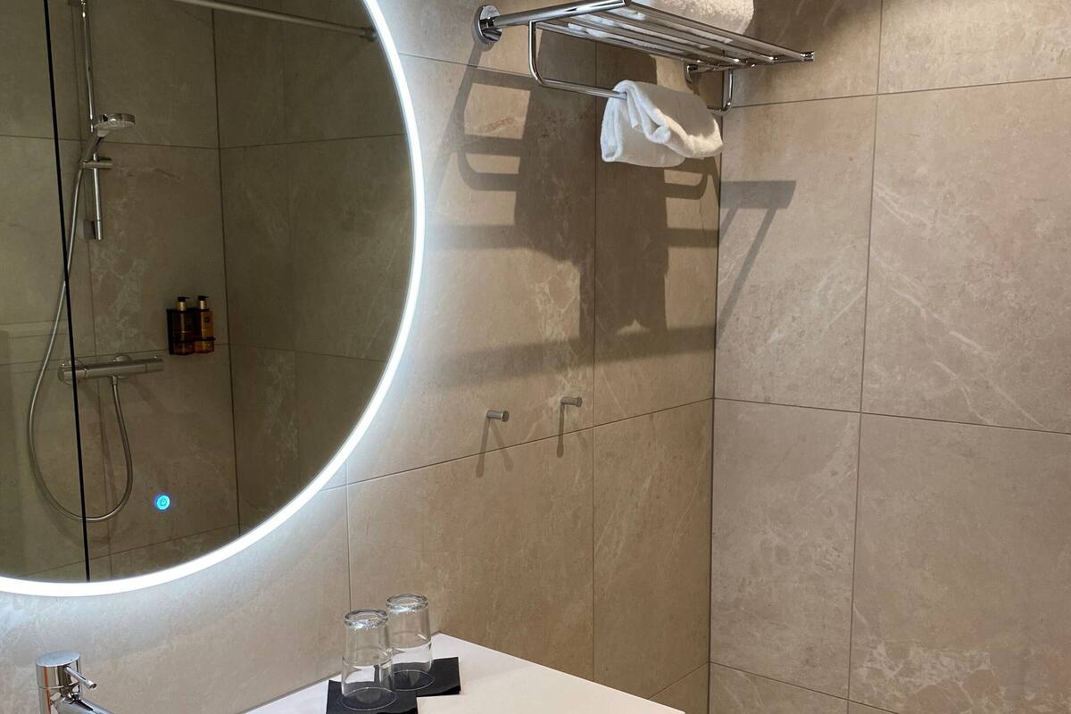 Un baño moderno con un espejo grande, un lavamanos y un perchero para toallas.
