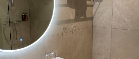 A modern bathroom with a large mirror, a sink, and a towel rack.