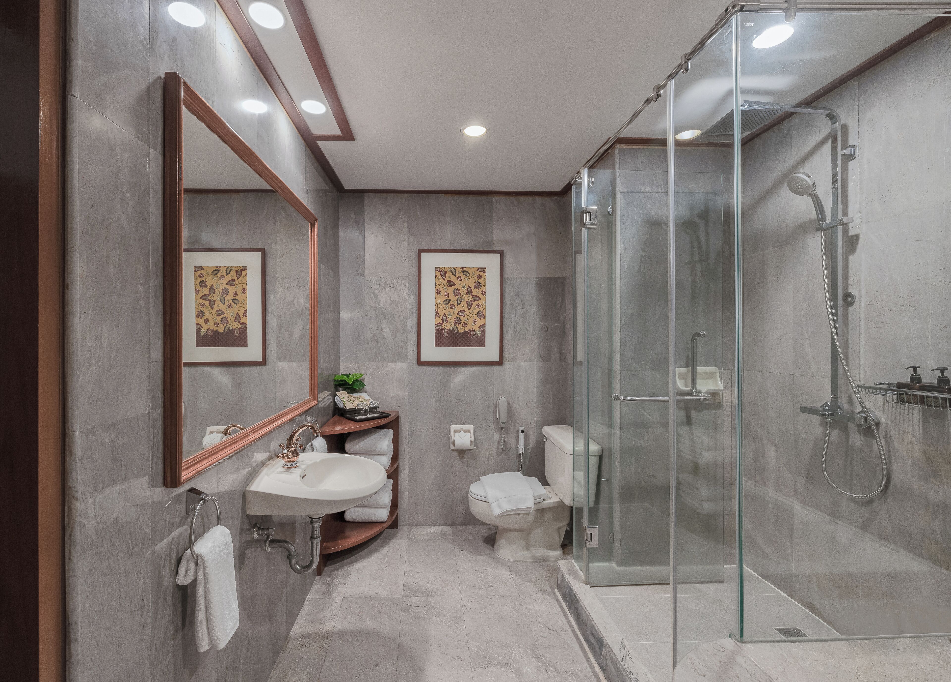A modern bathroom with a glass-enclosed shower, a sink with a mirror, and two toilets.
