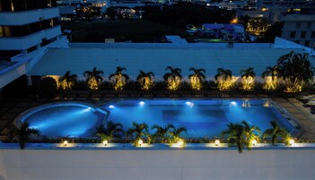 Una piscina al aire libre, sombrillas, sillones reclinables de piscina