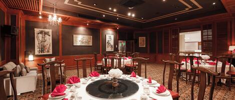 Un comedor formal con mesas redondas, servilletas rojas y vajilla blanca.