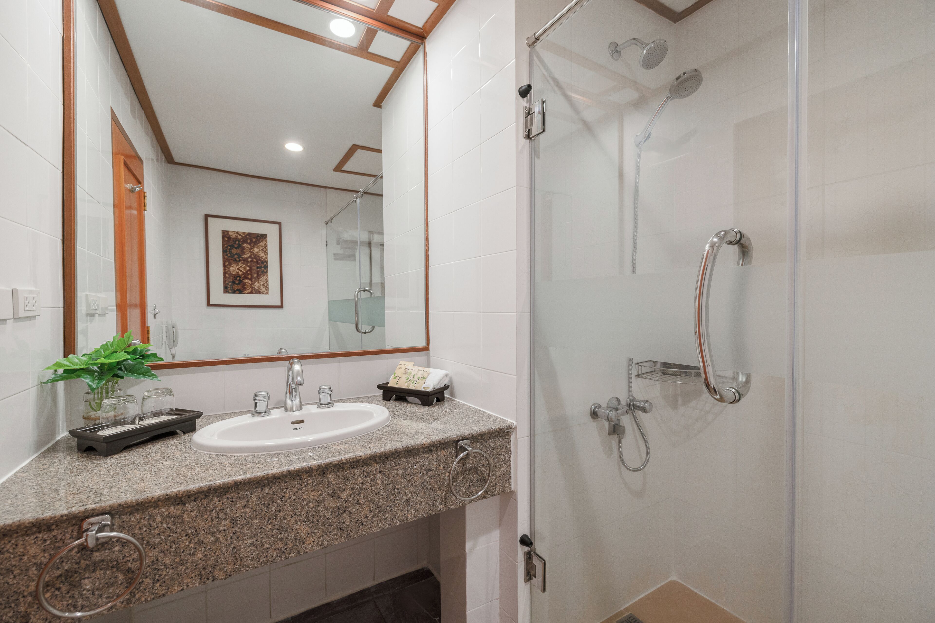 A modern bathroom with a granite countertop, a sink, a mirror, and a glass-enclosed shower area.
