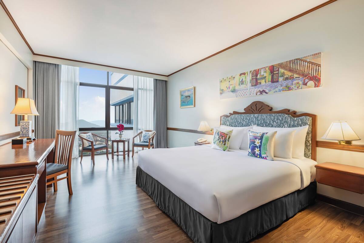 Een hotelkamer met een groot bed, een bureau, een stoel en een raam met uitzicht.