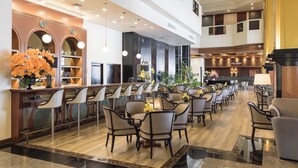 Un amplio vestíbulo de hotel con varias zonas de estar, un mostrador de recepción y un restaurante visible llamado "Royal Phuket".
