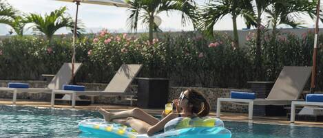 A pool area with lounge chairs and umbrellas.