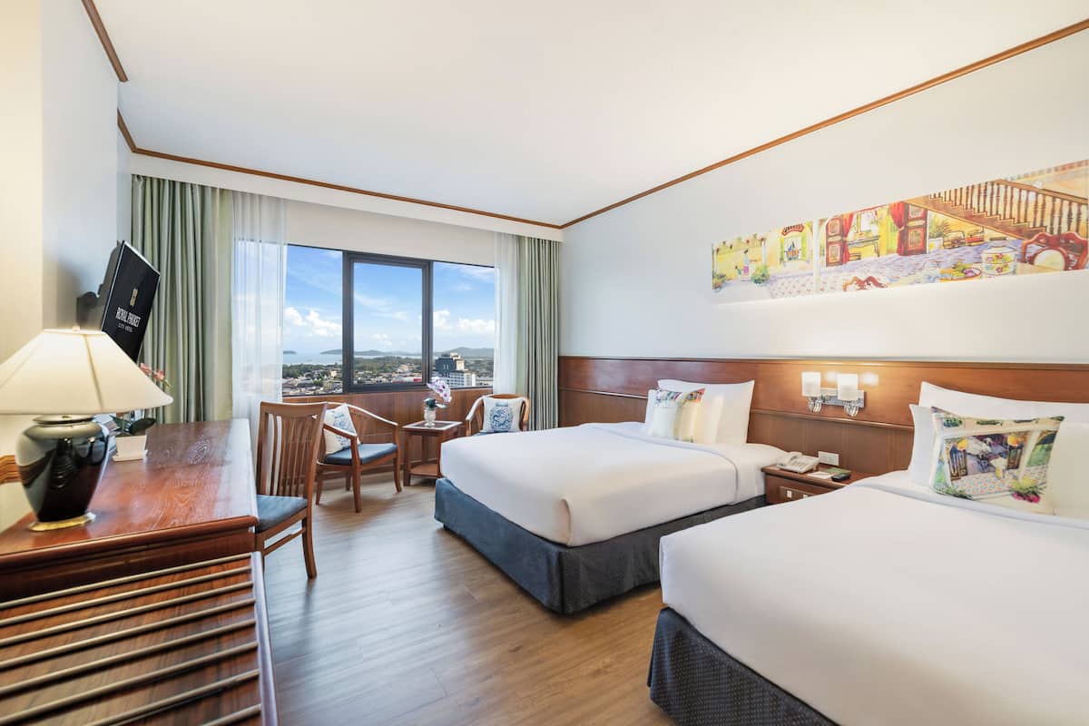 Hotelkamer met een bureau, twee bedden, een stoel, nachtkastje en een groot raam met uitzicht.