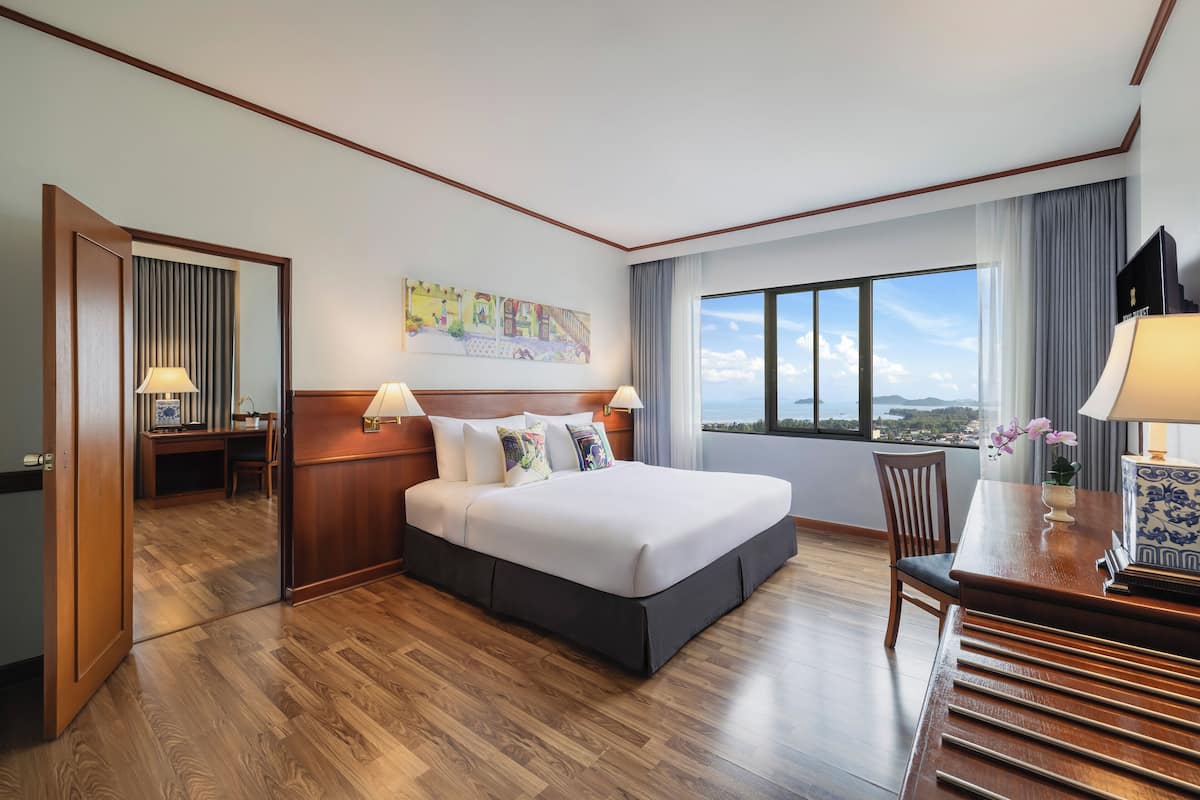 Een hotelkamer met een groot bed, een bureau, een stoel en uitzicht op de stad.