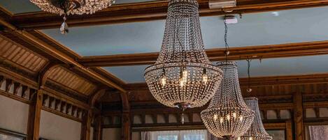 A dining area with wooden paneling, chandeliers, and framed artwork on the walls.