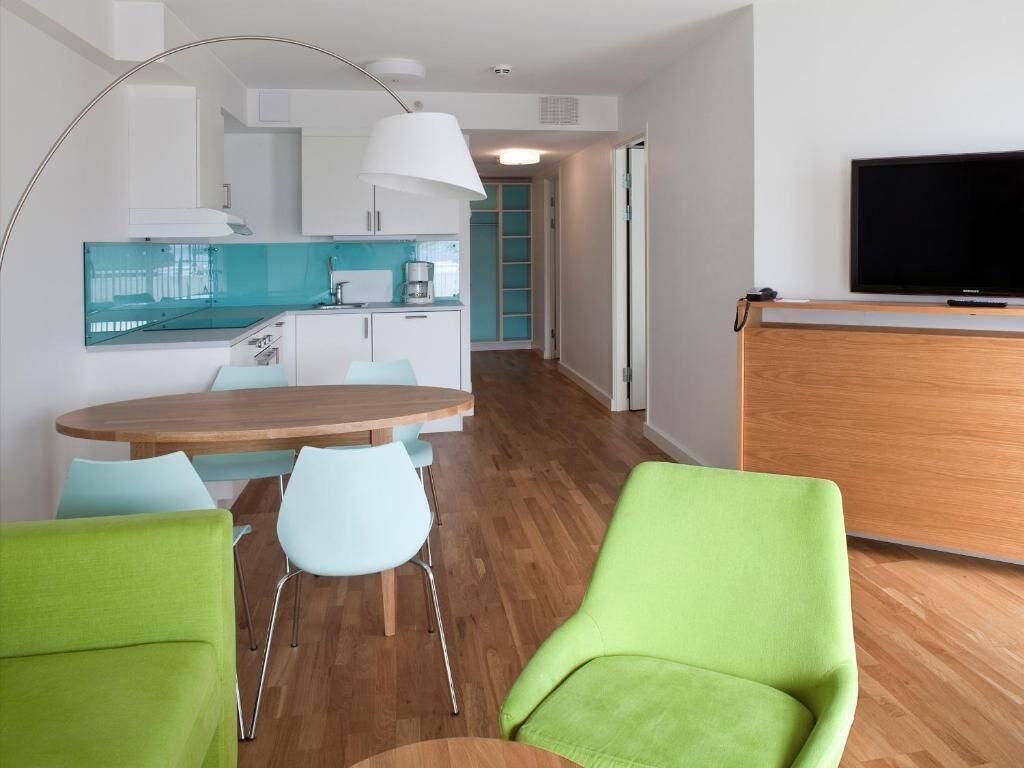 Una cocina moderna con armarios blancos, un salpicadero azul y una mesa de comedor de madera con dos sillas.