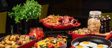 A variety of dishes including roasted potatoes, sautéed vegetables, fried eggs, and a dish with beans and bacon.