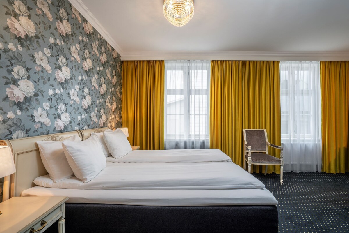 A hotel room with a large bed, a chair, a nightstand, and a lamp.