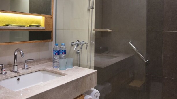 A modern bathroom with a glass-enclosed shower, a sink with a mirror, and a towel rack. - Hotel Santika Premiere Slipi Jakarta (Jakarta)