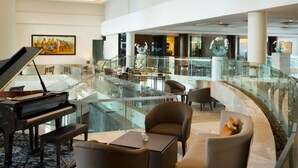 A spacious lobby with a grand piano, comfortable seating, a glass railing, and a view of the lower level. - Hotel Santika Premiere Slipi Jakarta (Jakarta)