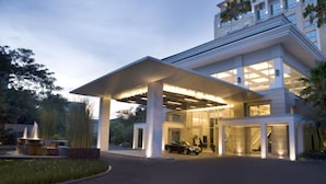 A modern hotel with a covered entrance, large windows, and a car parked in front. - Hotel Santika Premiere Slipi Jakarta (Jakarta)