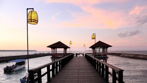 A wooden pier leading to two wooden gazebos with a boat docked at the end. - Grand Luley Manado (Manado)