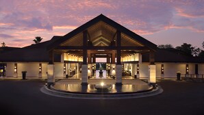 A hotel entrance with a covered walkway, a central fountain, and a landscaped area. - Grand Luley Manado (Manado)