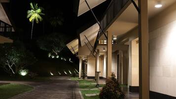 Un pasillo de hotel bien iluminado con un diseño arquitectónico moderno, que incluye una galería cubierta y un camino hacia la entrada.