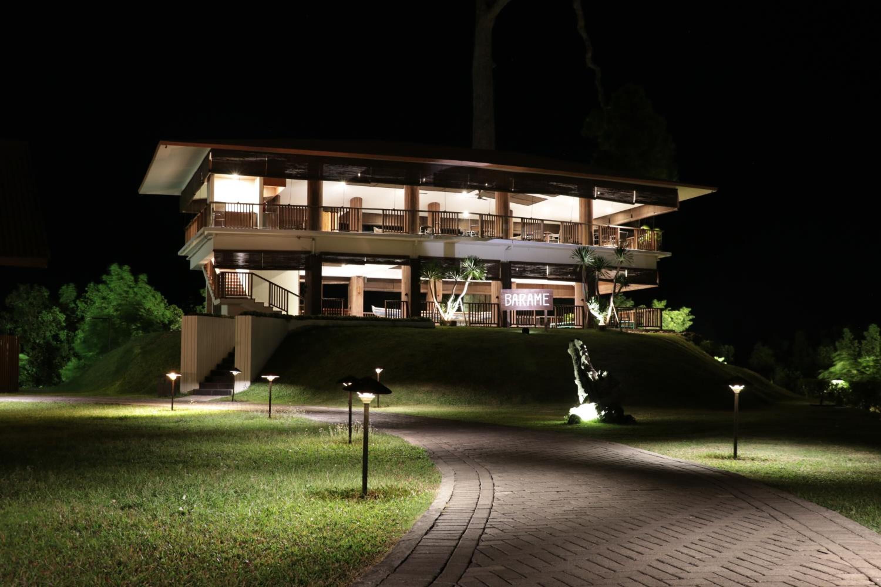 A multi-story hotel with a modern design, featuring balconies and a well-lit entrance.