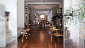 A modern interior with a wooden floor, a sofa, a dining area with chairs, and a kitchen in the background.