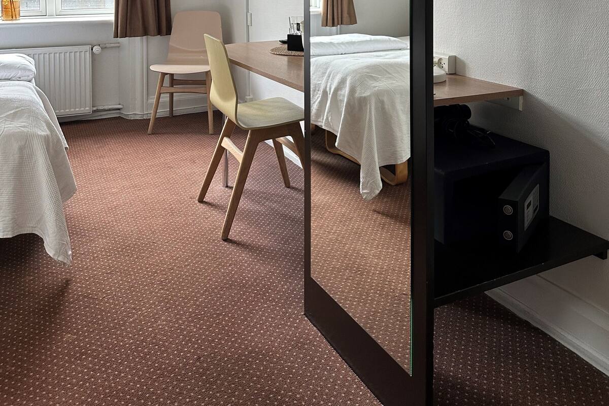 A hotel room with a bed, a desk, a chair, a TV, and a wardrobe.