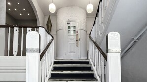 A grand staircase with white balustrades, a central landing with a door, and a decorative ceiling light fixture.