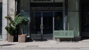 A building with a green awning, a bench, and a street lamp.