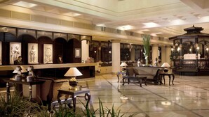 A spacious lobby with a reception desk, seating area, and decorative elements like sculptures and plants.