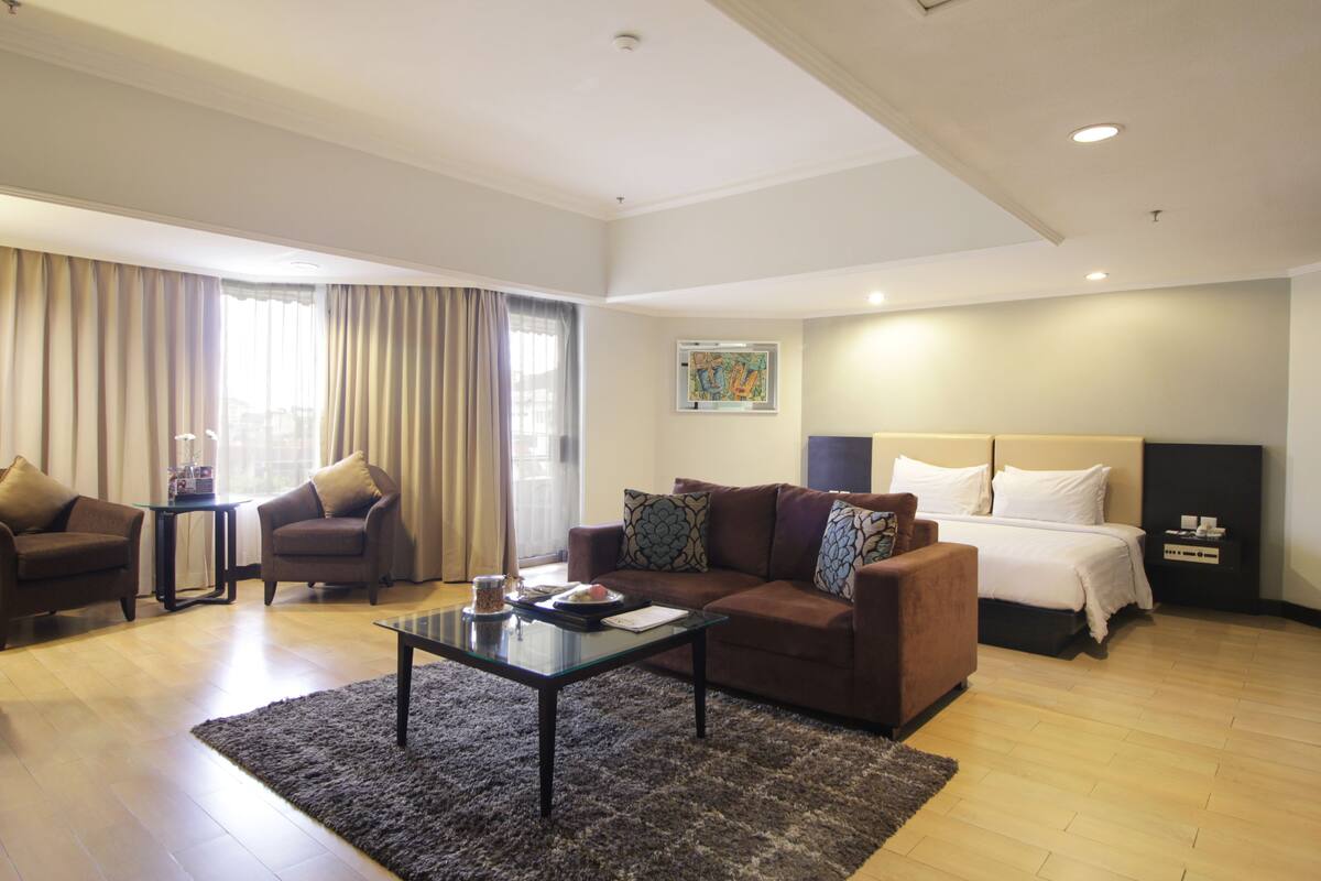 Una habitación de hotel moderna con una cama grande, un sofá, una mesa de centro y un escritorio.