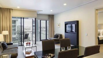 Habitación de hotel moderna con balcón, televisión de pantalla plana, mesa de comedor y sofá.