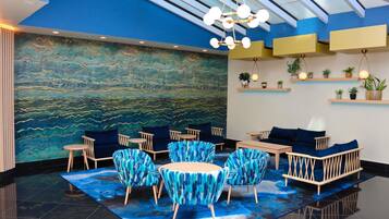 A modern interior with a blue and green abstract mural, a glass ceiling, and a seating area with blue patterned chairs and sofas.