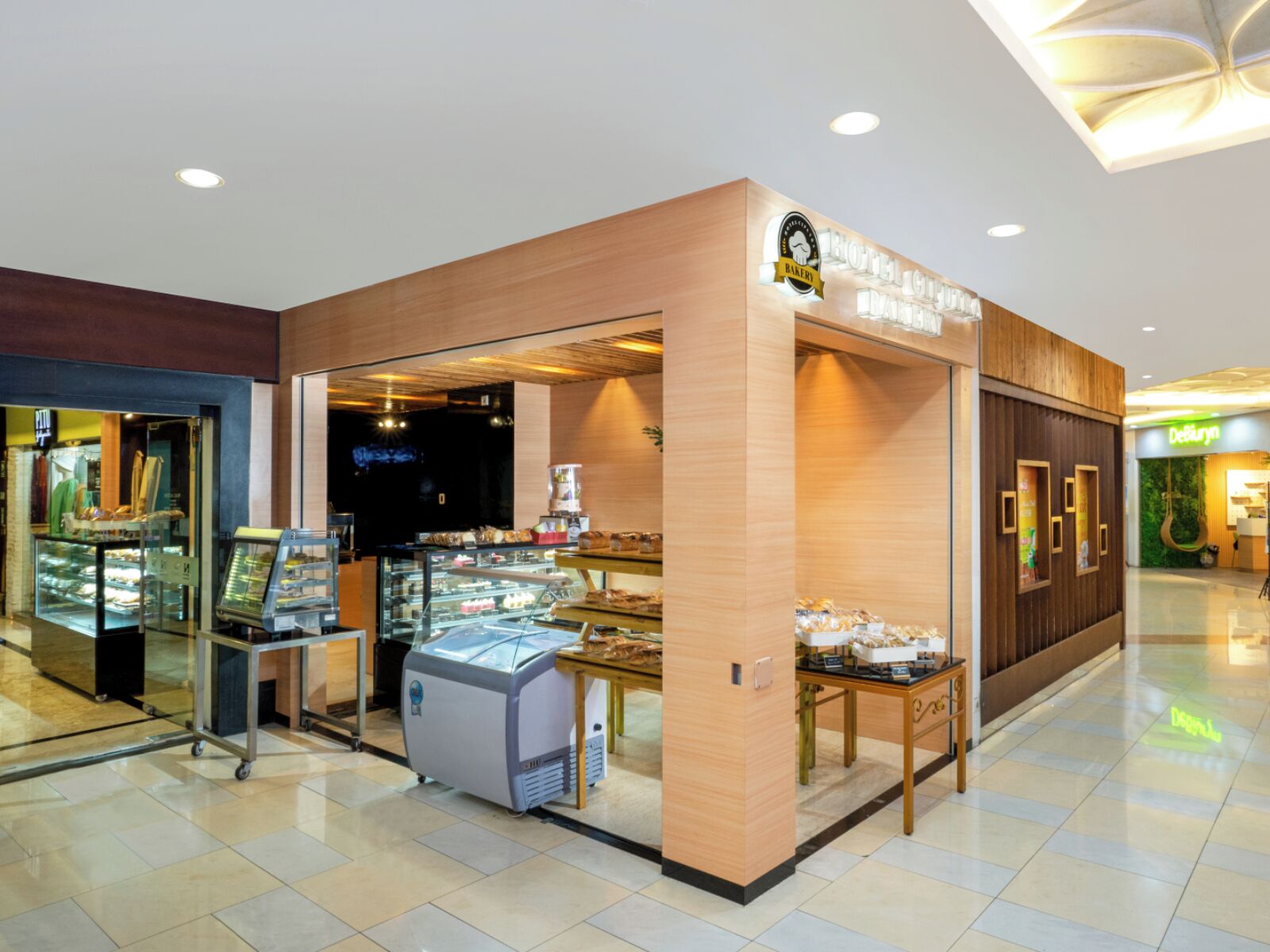 A bakery with a display case and a coffee machine, located in a shopping mall.