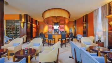 Un vestíbulo de hotel con zona de bar, asientos y exhibición de vinos.