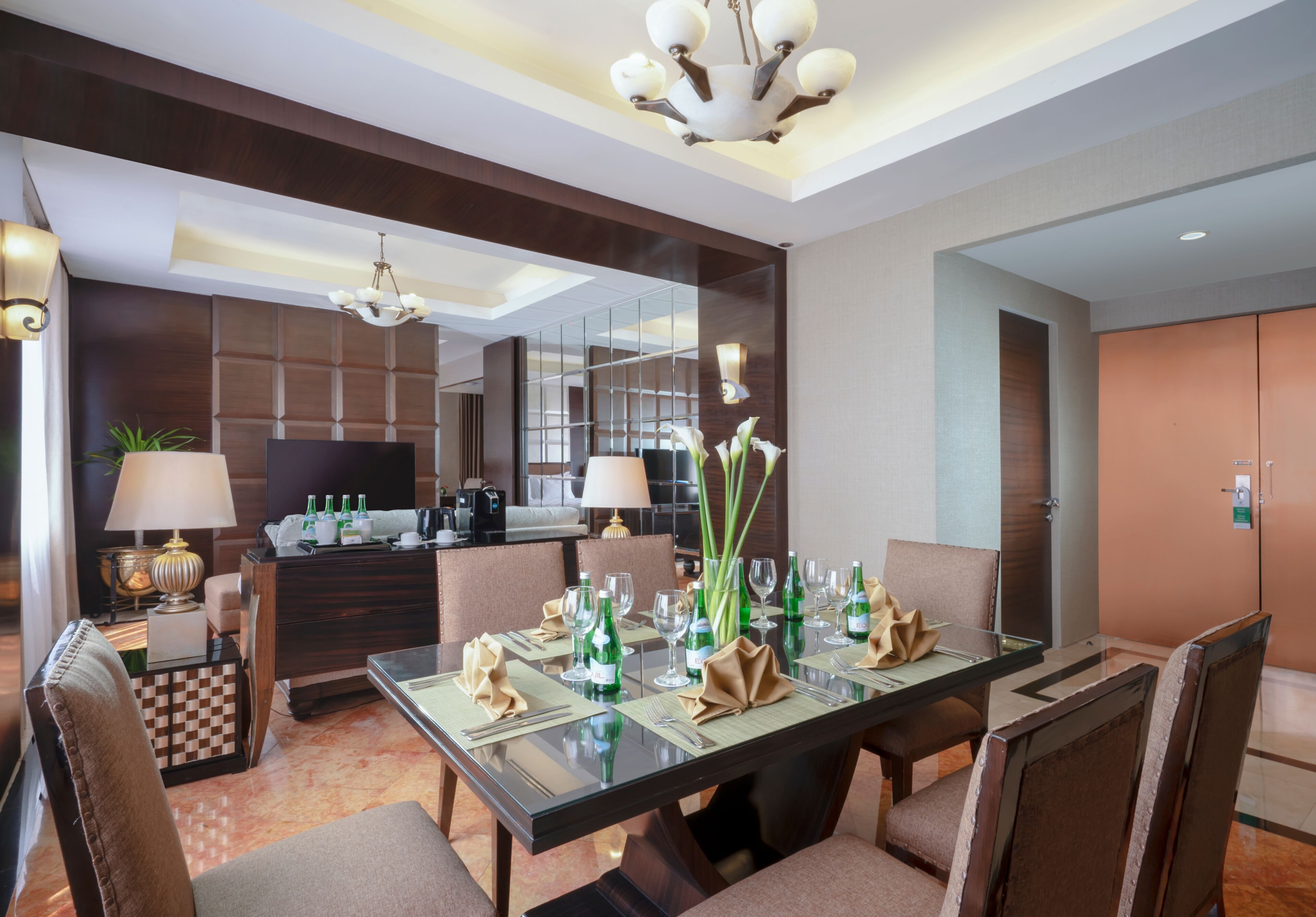 A hotel dining area with a glass table set for six, surrounded by cushioned chairs.