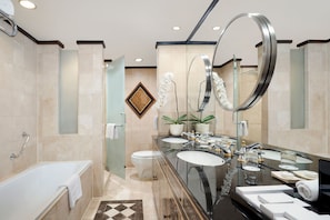 Un baño moderno con una bañera, dos lavamanos, un espejo grande y un inodoro.